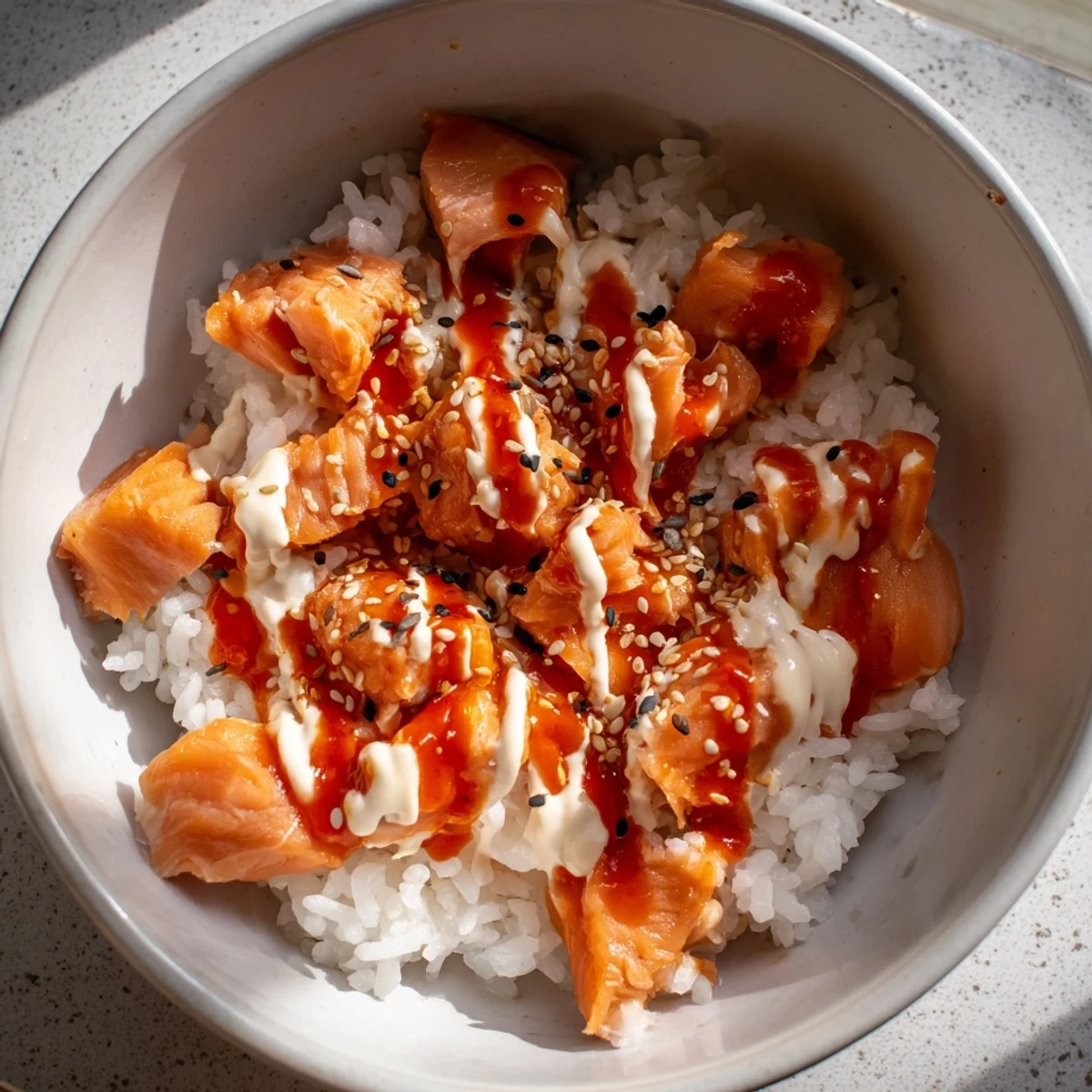 Ready-to-eat Emily Mariko salmon rice bowl with seasoned rice, tender salmon, and crisp seaweed sheets for wrapping bites, served alongside sliced green onions.