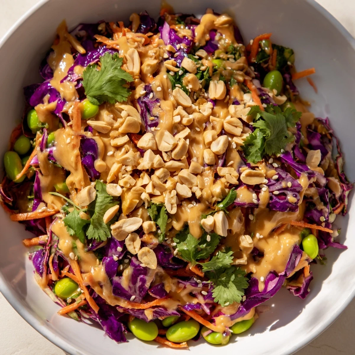 Vibrant and fresh Crunchy Thai Peanut Salad with crisp shredded cabbage, shredded carrots, and edamame, drizzled with a tangy peanut-lime dressing and topped with sesame seeds.