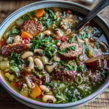 Close-up of a warm bowl of Black-Eyed Peas and Sausage Soup topped with fresh parsley and grated Parmesan.