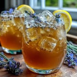 Refreshing lavender honey lemonade pitcher with ice, garnished with lemon slices and lavender sprigs.