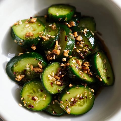 Crisp cucumber slices glisten in a jar with minced garlic, ready to be dressed in a savory sesame soy sauce.
