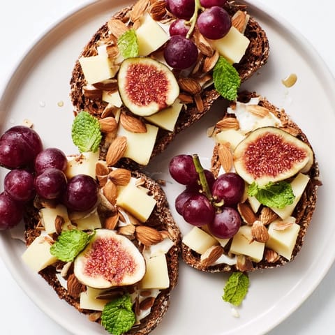 This Harvest Scythe arrangement showcases a rustic spread of bread, grains, cheeses, and colorful, seasonal fruits.