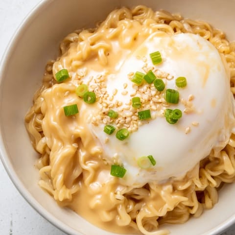 Creamy and cheesy Instant Cheese Ramen Bowl garnished with fresh green onions and sesame seeds.
