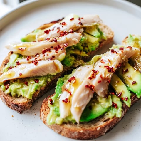 Savory-smoky grilled chicken with a honey drizzle tops avocado toast, creating a vibrant and delicious brunch recipe.