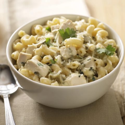 Steaming skillet of Green Chili Chicken Mac garnished with fresh cilantro and sliced jalapeño for a Southwestern twist.  