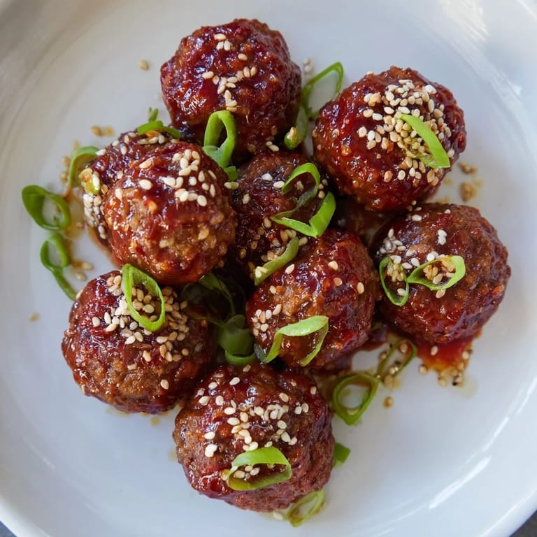 A close-up of sweet and spicy Sriracha Honey Meatballs, a perfect American-Asian fusion appetizer.
