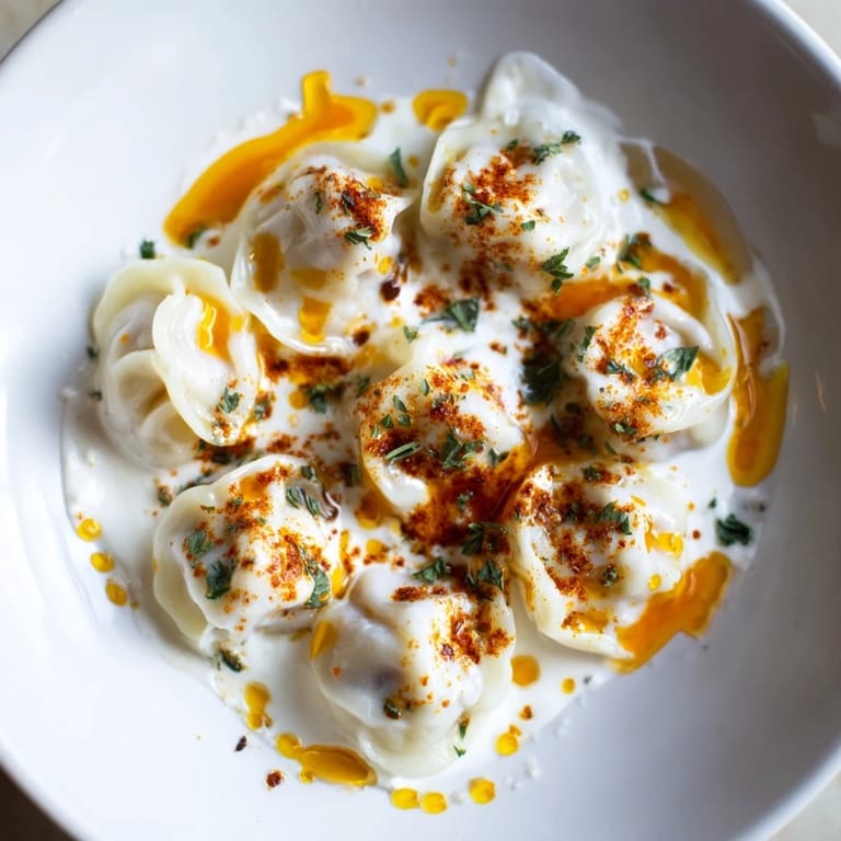 Golden, perfectly cooked Turkish cheesy manti served swimming in creamy yogurt and flavorful butter.