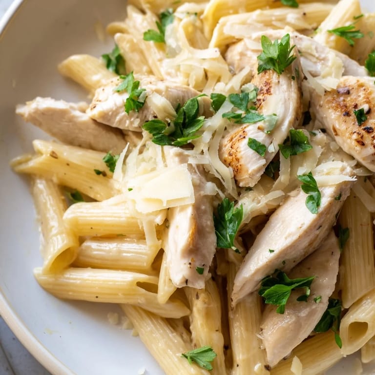 A close-up of Roasted Garlic Chicken Penne, featuring tender chicken pieces and silky cream sauce clinging to each pasta tube.