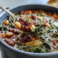 Soul Food Black-Eyed Pea and Collard Green Stew in a rustic Dutch oven, steaming with smoky spices and vibrant greens, perfect for a cozy Southern dinner.